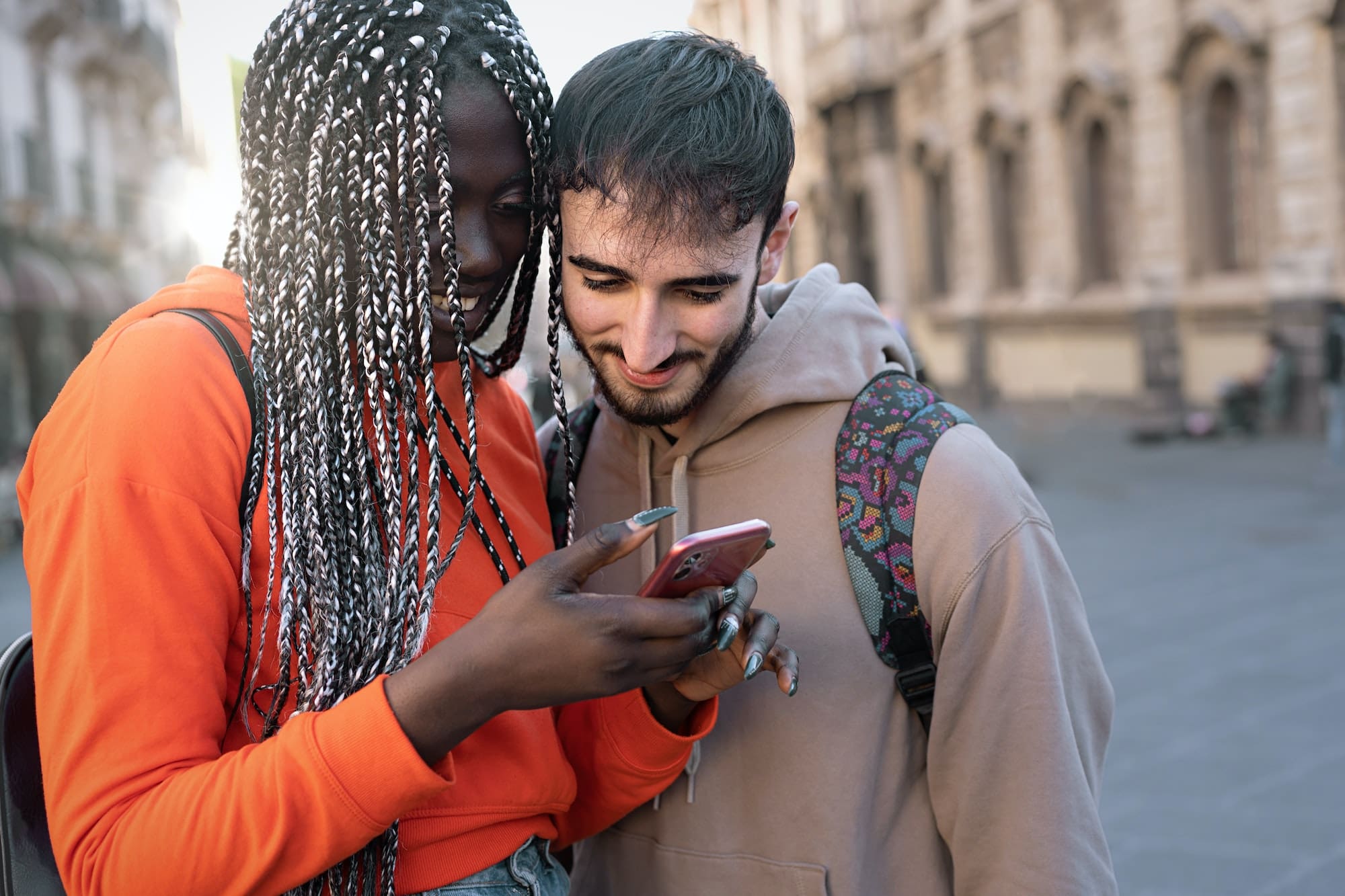 Multi-ethnic engaged couple of tourists watching content on the smartphone