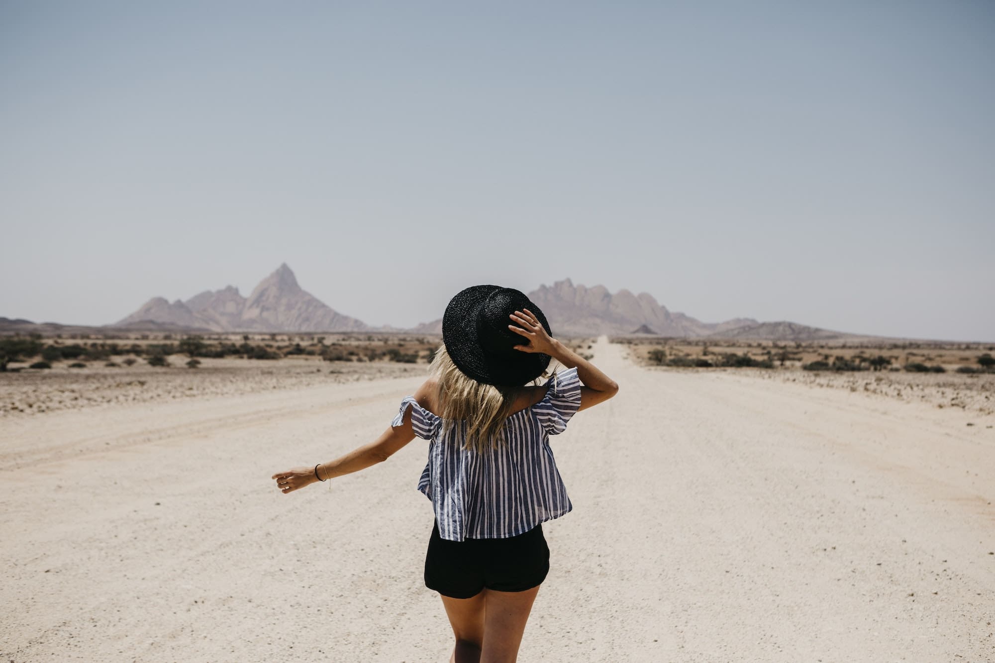 Namibia, woman walking on the road to Spitzkoppe