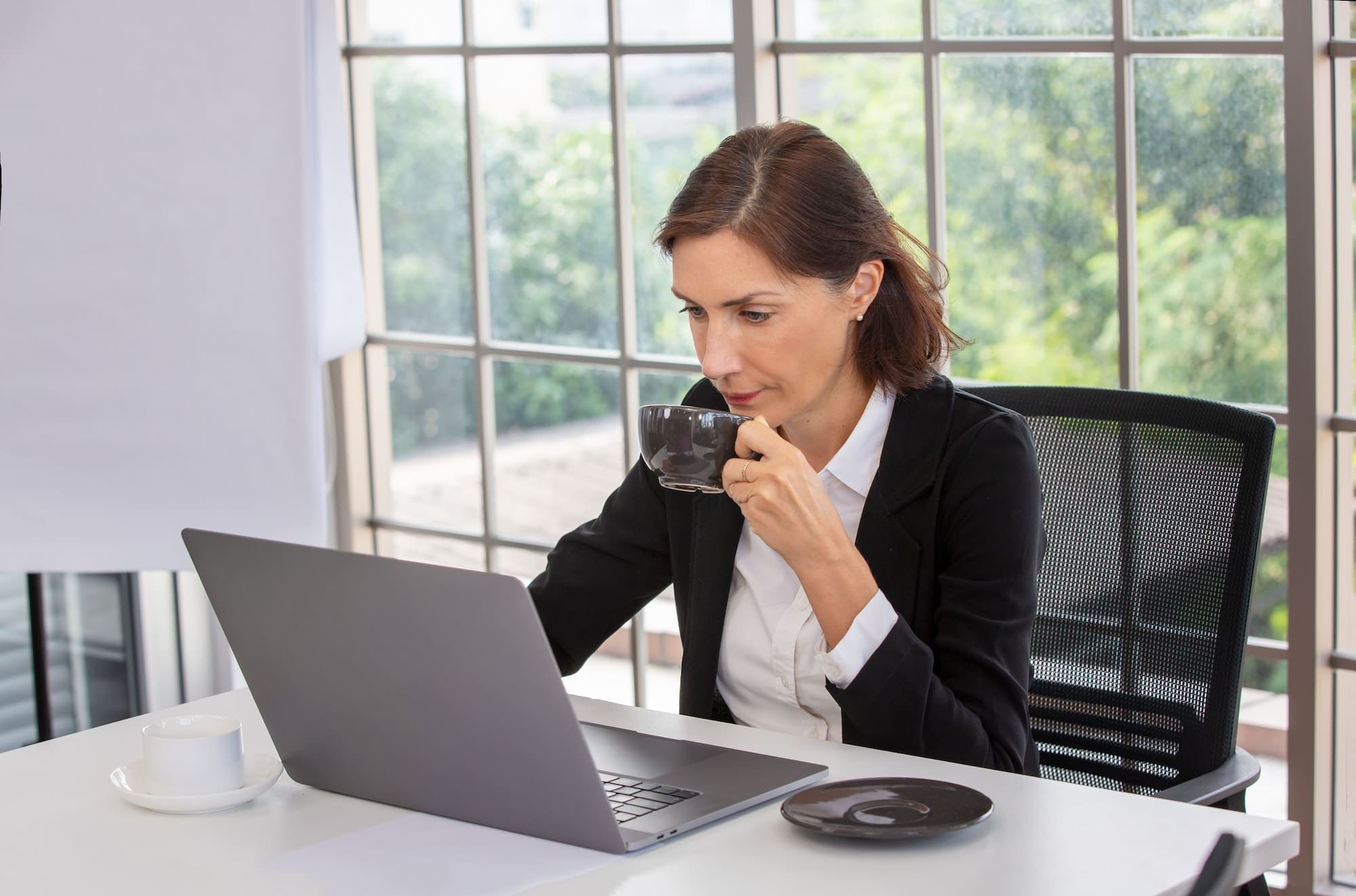 woman drinking coffee while working online from home