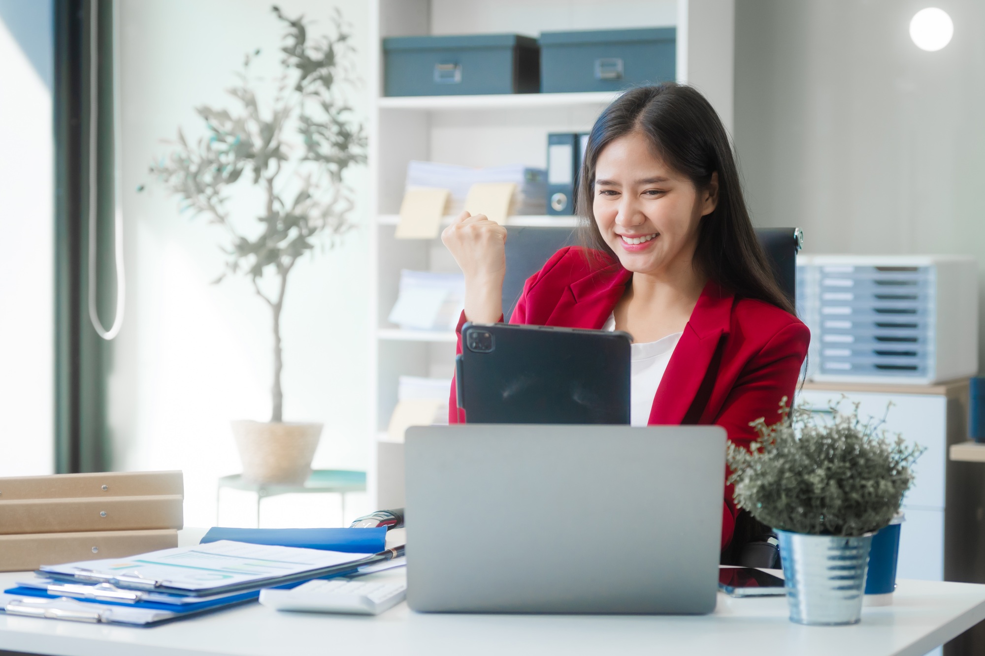 Young Asian woman at desk, strategizing marketing funnels and SEO in a bright office setting.