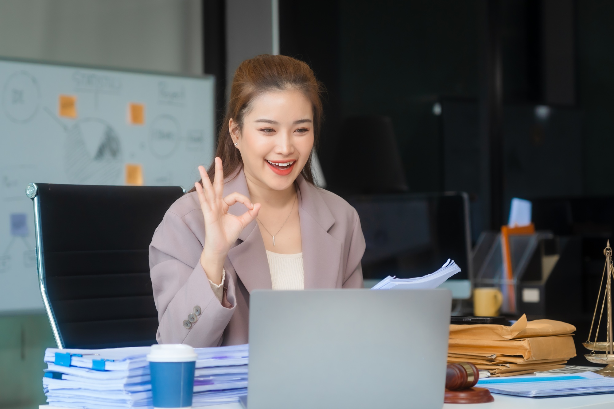 Asian businesswoman in formal attire works on laptop, on corporate law and marketing strategy.
